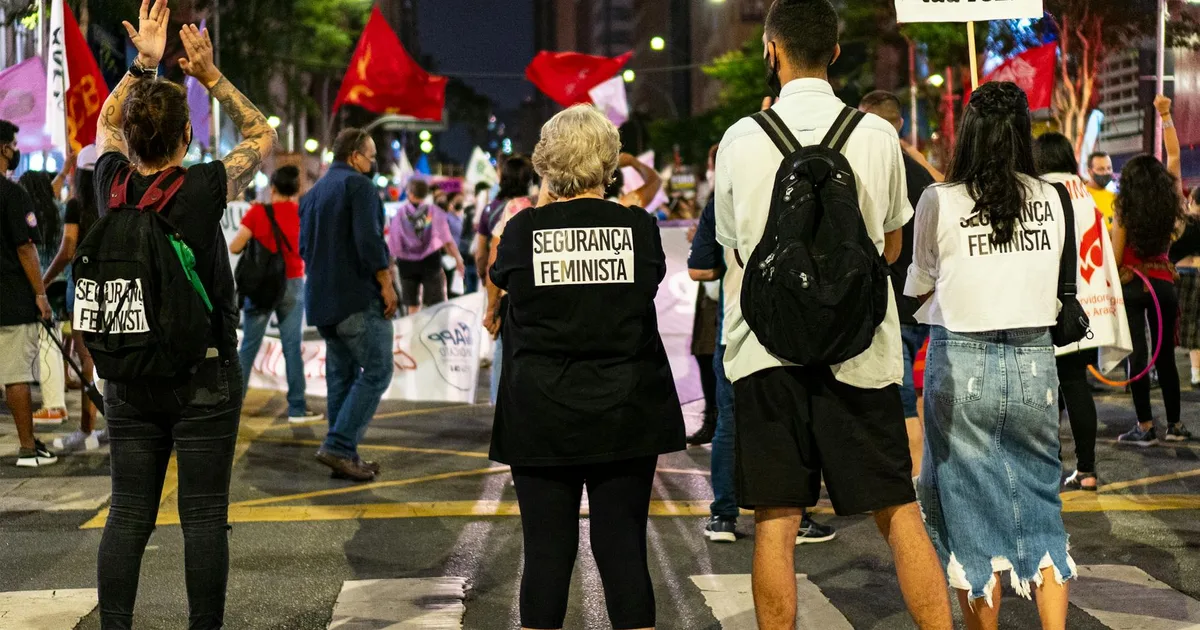 Mãos de uma criança segurando foto da mãe, com documentos trabalhistas em cima de uma mesa