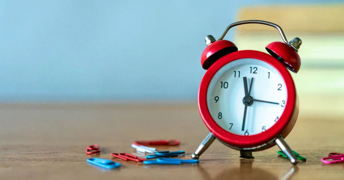 Trabalhador olhando para o relógio enquanto consulta um advogado sobre horas extras não pagas