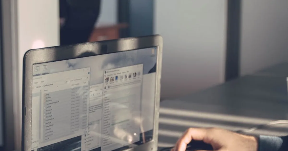 Tela de computador com código de software e documento de contrato trabalhista ao lado
