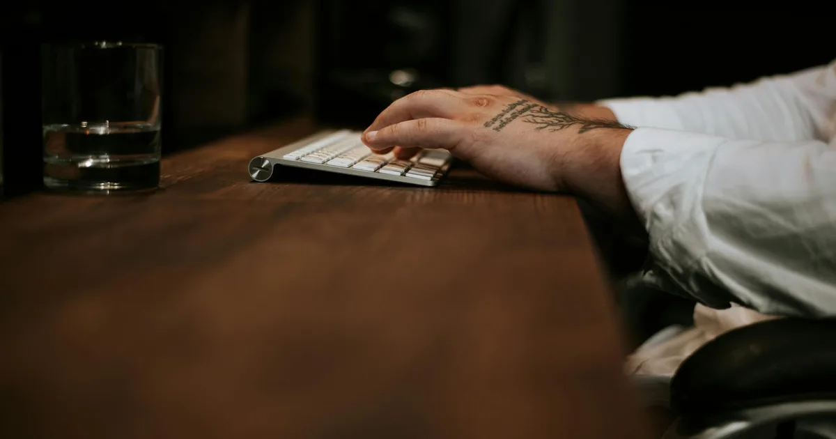 Trabalhador com dor no pulso sentado em mesa de escritório, consultando um advogado trabalhista